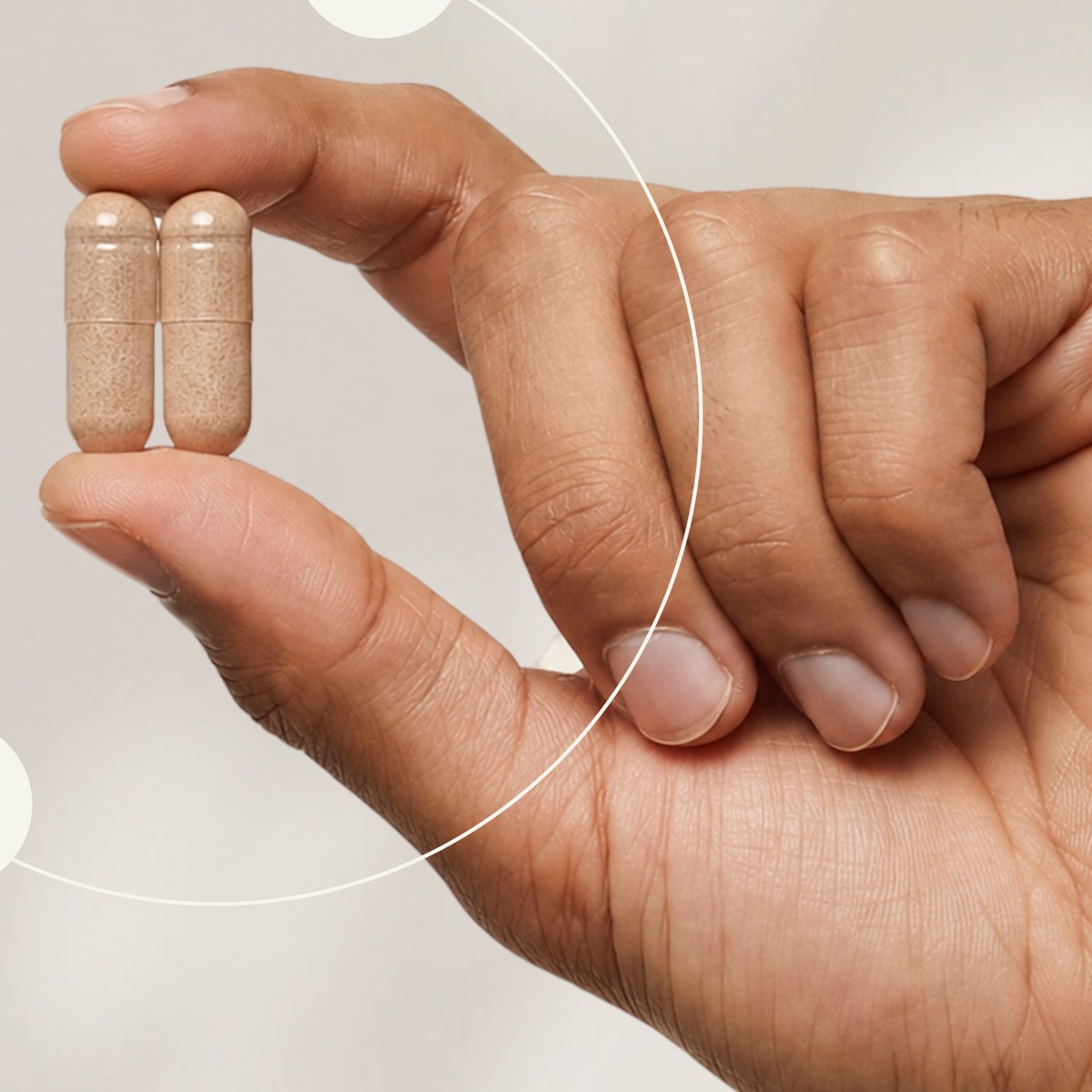 A hand holding two capsules